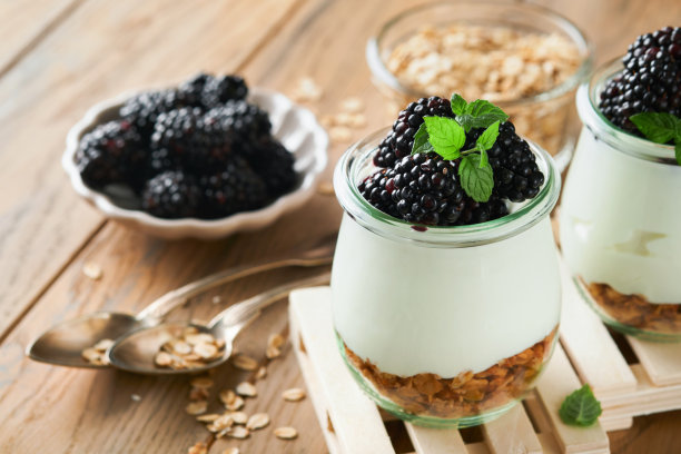 酸奶配格兰诺拉麦片，黑莓浆果水果和什锦麦片，装在木制背景的玻璃罐中。健康的早餐概念。健康的早餐，俯视图图片下载