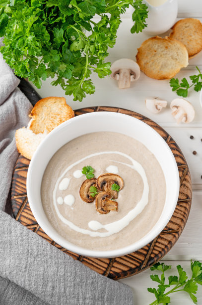 蘑菇奶油汤，奶油，面包丁和香草在白色的木制背景。美味的食物。图片下载