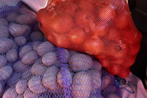 在市场上用网买的土豆和洋葱躺在一辆汽车的后备箱里。图片下载