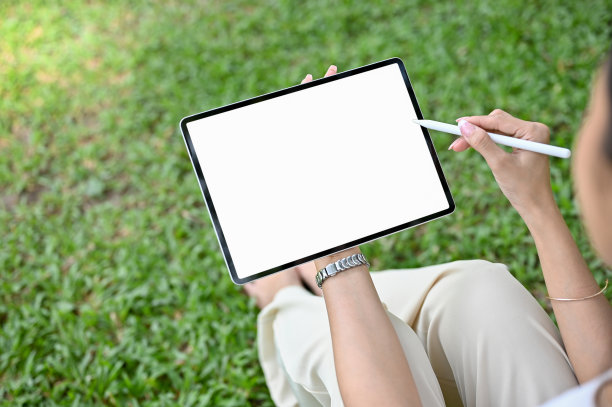 特写，亚洲女性在公园放松时使用平板电脑。平板白屏模型图片下载