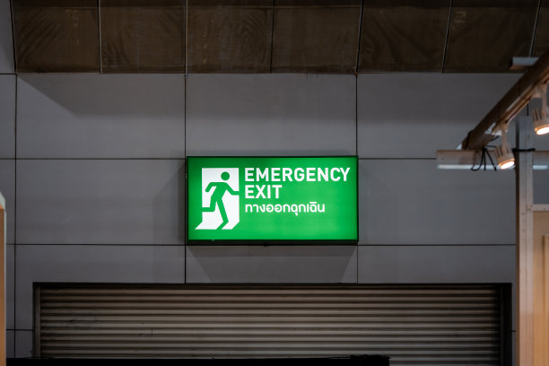 展厅墙壁上放置了大型紧急出口标志绿灯箱。绿色灯箱上的泰国语字母表示“出口”。图片下载