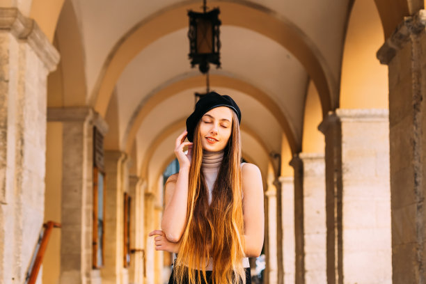 特写的女孩长发和黑色贝雷帽，站在拱门下灯笼和闭着她的眼睛图片下载