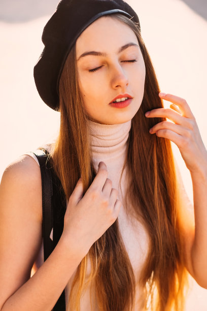 一张温柔的照片，一个女孩戴着黑色贝雷帽，在一个美丽的阳光灿烂的日子里闭上了眼睛图片下载