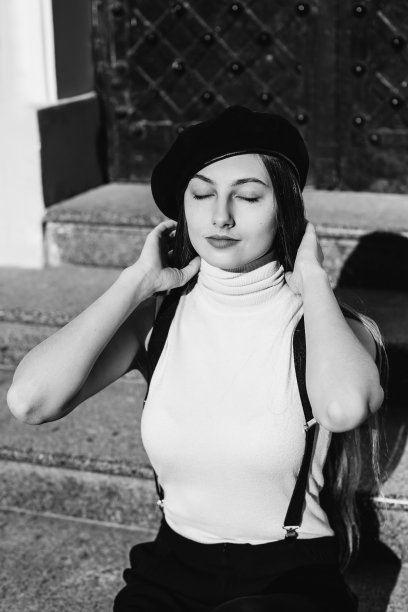 一个快乐的女孩闭上眼睛，把头发固定在楼梯上的白色白色照片上图片下载