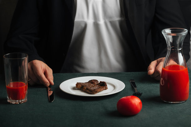 男人在家里吃晚饭，肉和番茄汁图片下载