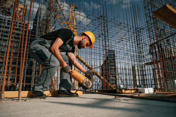 用磨床切割金属件。一个穿制服的人正在建筑工地工作图片下载