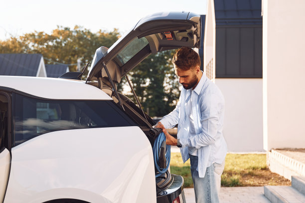 从卡车上拿充电线。年轻有型男子在白天与电动汽车图片下载