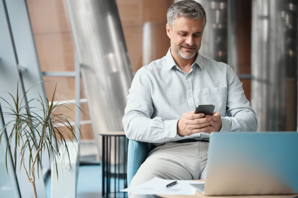 男人坐在椅子上，手里拿着手机图片下载