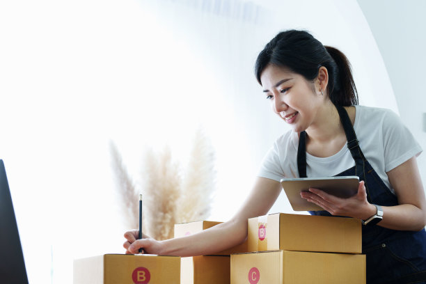 创业创业的独立亚洲女性微笑着用平板电脑与愉快的成功网上营销包装盒项目和中小企业送货理念图片下载