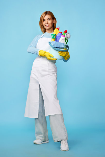 妇女戴橡胶手套和清洁围裙与清洁用品图片下载