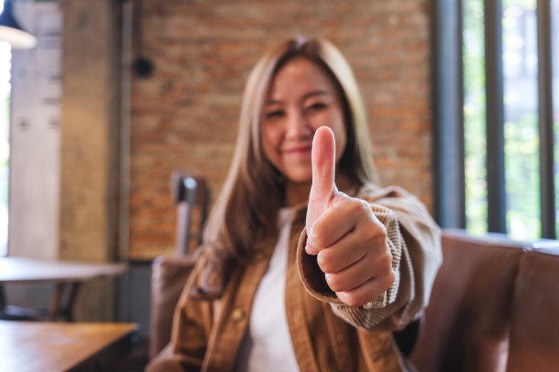 一个年轻的亚洲妇女做着竖起大拇指的手势图片下载