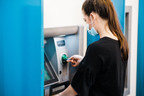 戴口罩的妇女在银行自动柜员机内照料传染病图片下载