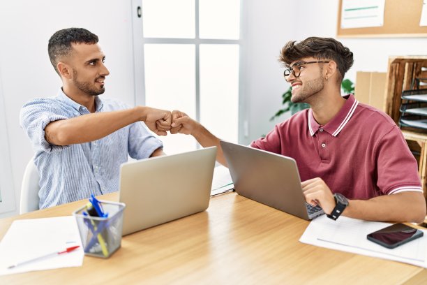 两个商务人员在办公室里愉快地碰碰拳头。图片下载