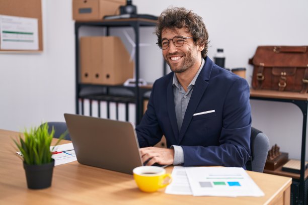 年轻的西班牙人工作人员使用笔记本电脑在办公室工作图片下载