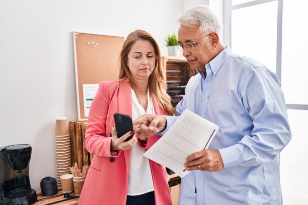 中年男女上班族在办公室使用智能手机阅读文件图片下载