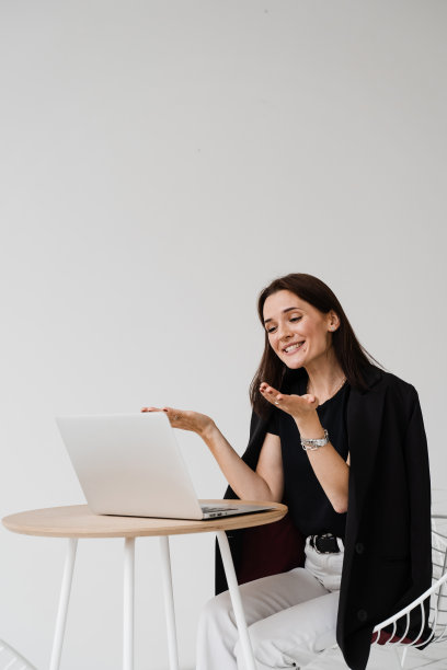 视频会议与朋友和同事和乐趣远程在线后成功的项目。带着笔记本电脑微笑的女孩，笑着和同事讨论工作中有趣的情况。图片下载