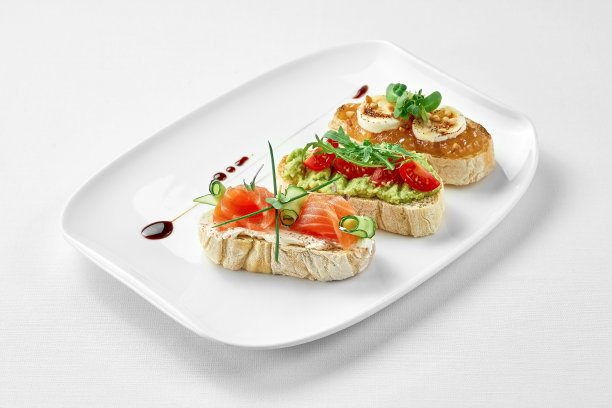 一套意式烤面包配三文鱼，牛油果和山羊奶酪在白色背景的白色盘子里。特写,有选择性的重点。图片下载