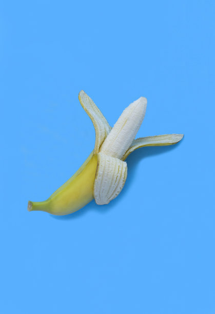 蓝色背景上剥了黄皮的香蕉。特写镜头。副本的空间。图片下载