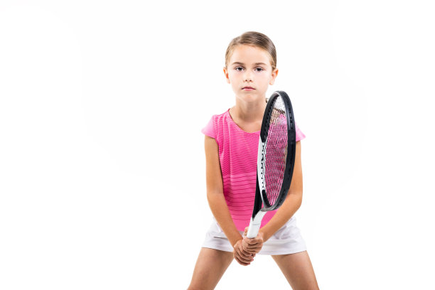 身穿粉红色衣服的年轻女网球运动员。小女孩摆姿势与球拍和球孤立在白色背景。图片下载