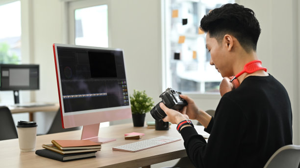 后视图年轻的男性视频编辑编辑音频电影蒙太奇与专业电脑在创意办公室工作室。图片下载