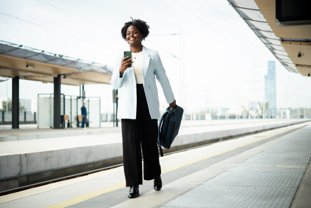 年轻的非裔美国女商人在火车站用智能手机图片下载