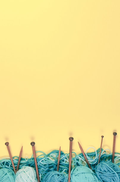 黄色背景的棕色木制针织针和针织羊毛。俯视图图片下载