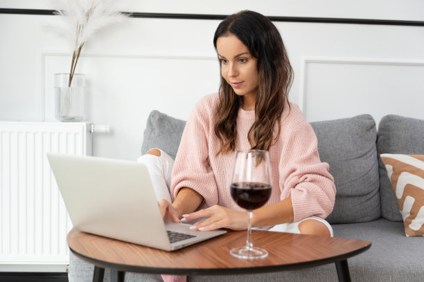 女人坐在沙发上，端着一杯红酒图片下载