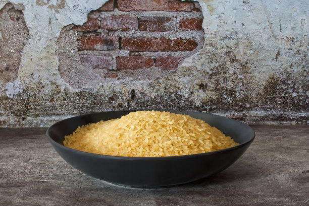 生米黄色在黑色盘子孤立在砖墙背景图片下载