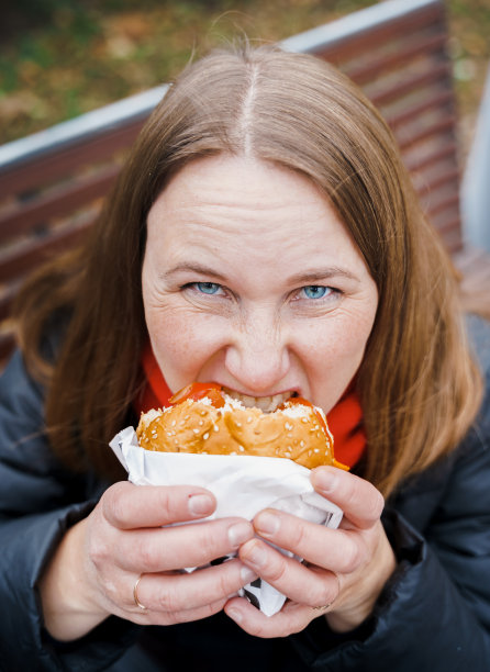 女孩，吃大汉堡的女人，芝士汉堡。垃圾、油腻、美味的街头食品。带走汉堡。午休时间在户外公园坐在长凳上。不健康的饮食。周末放松。身体积极的。超重的问题图片下载