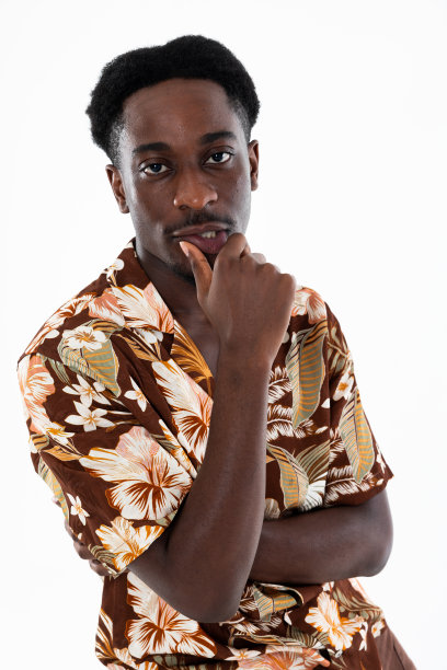 特写肖像的非裔美国人看着相机穿着时髦的发型和衬衫上印着花看着相机站在白色背景的工作室孤立图片下载