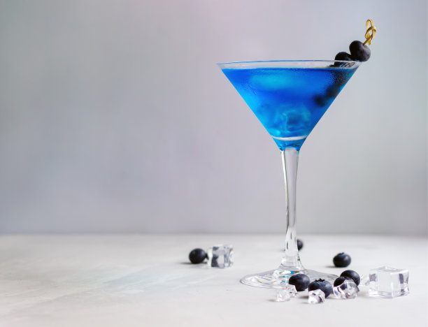马提尼杯蓝色鸡尾酒，加冰块和蓝莓图片下载
