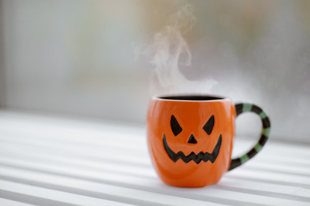 在窗台上用热咖啡把南瓜南瓜灯笼形状的杯子卷起来图片下载