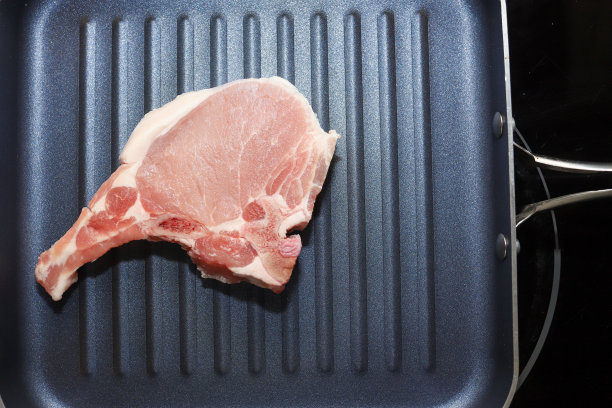 在煎锅中未煮熟的猪排图片下载