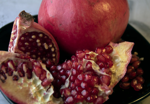 一个成熟多汁的红石榴放在黑色盘子里图片下载