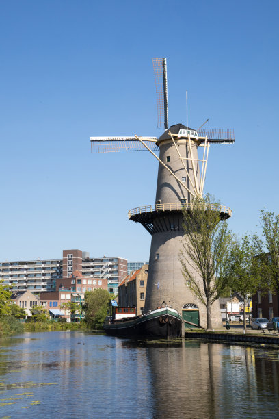 古老的历史荷兰风车旁边的运河水边与船在Schiedam老城中心，荷兰。城市图片下载