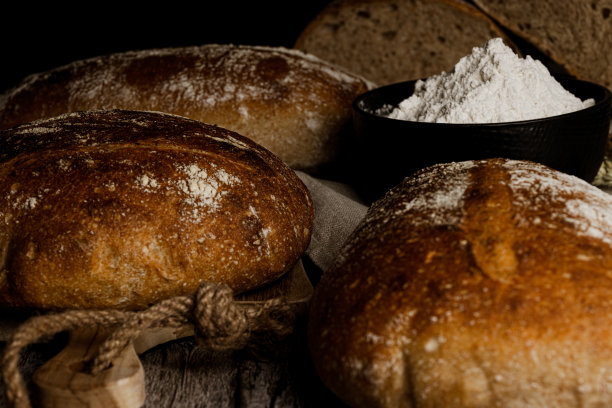 水平照片的工匠面包从全麦面粉与罐面粉在乡村木桌和黑色背景图片下载