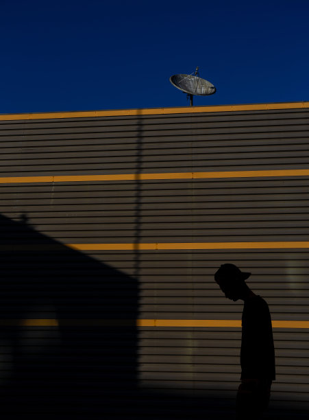 一个关闭的天线对着深蓝色的天空和一个悲伤的男孩的剪影走向一个没有接待的家。图片下载