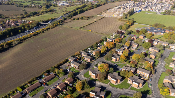 英国西约克郡韦克菲尔德镇的无人机照片，展示了典型的英式英国住宅小区和靠近农田和高速公路的道路，拍摄于秋天。图片下载