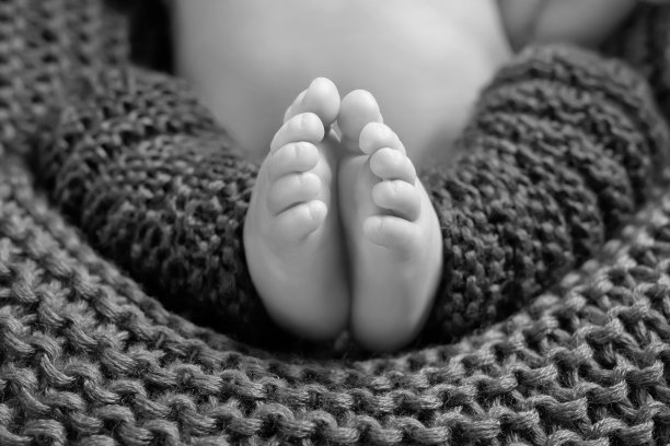 近距离的图片新生的婴儿脚上针织格纹。小宝宝的脚特写。幸福的家庭的概念。美丽的概念形象的孕产妇。黑白图像图片下载