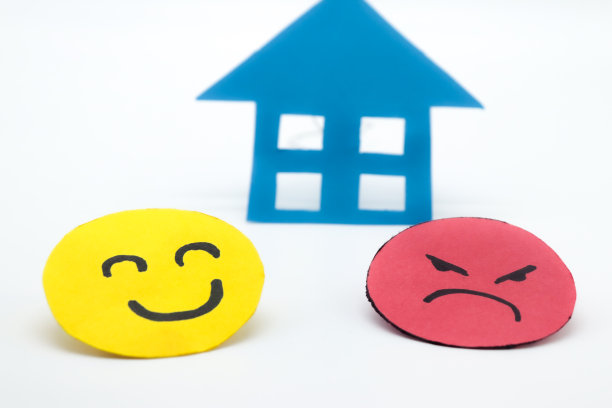 黄色的剪纸笑脸，另一个生气的红脸和蓝色的纸房子。在白色背景上。对家里问题的概念，对房地产行业的看法，对房子的买卖图片下载