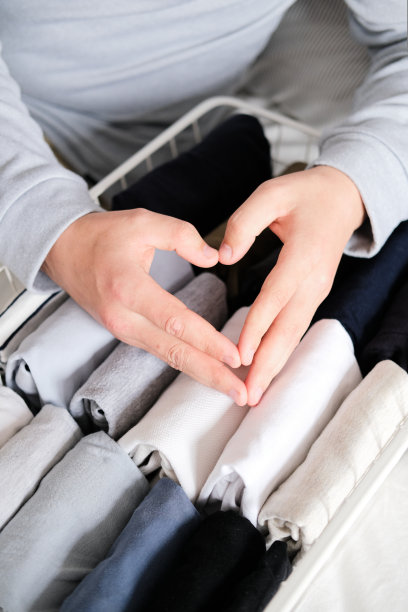 一个男人的手的特写整理的东西在网格存储容器。垂直存放衣物。图片下载