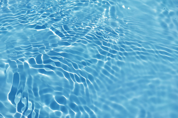 离焦模糊透明的蓝色清澈平静的水面纹理带有水花、气泡。粼粼碧水涟漪背景。游泳池的水面。蓝色的泡泡水闪闪发光。图片下载
