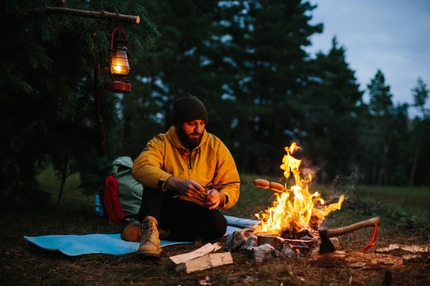 一个孤独的流浪者在山上的篝火旁吃晚餐。图片下载