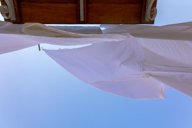 希腊塞米岛渔村的晾衣绳上晾晒着白色亚麻。雪白的床单在风中散落。底视图图片下载