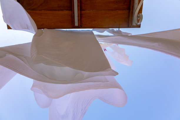 希腊塞米岛渔村的晾衣绳上晾晒着白色亚麻。雪白的床单在风中散落。底视图图片下载