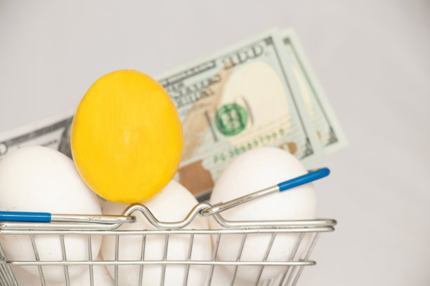 一个金色的鸡蛋和白色的鸡蛋躺在超市的篮子里，旁边是白色背景下的美元，也就是钱图片下载