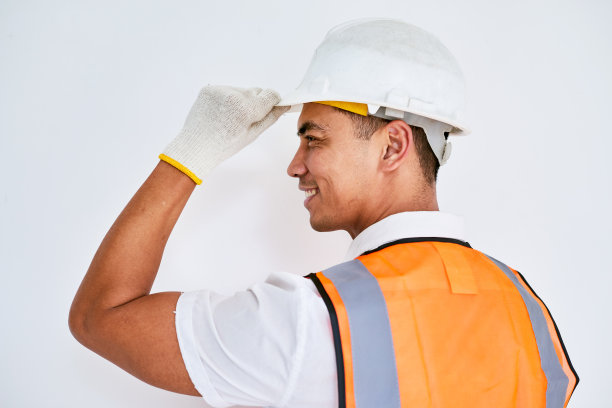 一名亚洲建筑工人的肖像，朝左脱帽致意图片下载