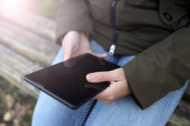 在公园的长凳上，一位女士正在户外的平板电脑上工作图片下载