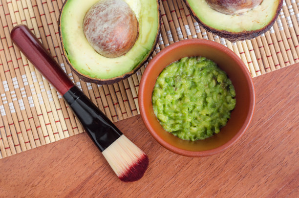 新鲜的牛油果泥放在小陶碗里，化妆刷。自制面膜、天然美容及水疗配方。俯视图，复制空间。图片下载