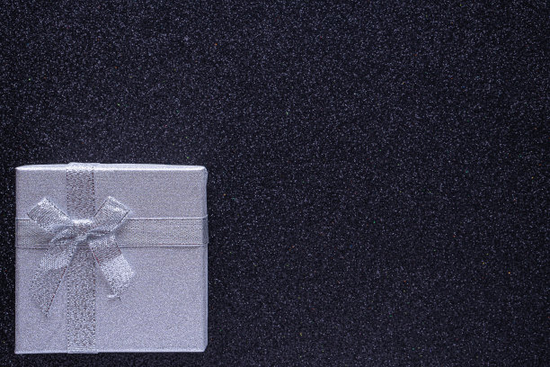 银色礼盒上闪闪发光的黑色背景与复制空间。前视图。圣诞节，情人节或生日派对的概念。贺卡,框架。平的。图片下载